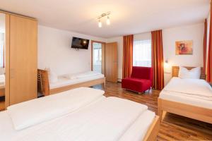 ein Hotelzimmer mit 2 Betten und einem roten Stuhl in der Unterkunft Gästehaus Sahin in Bartholomäberg