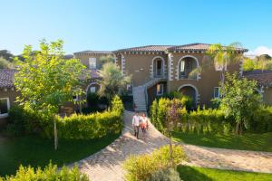 a group of people walking in front of a house at Is Serenas Badesi Resort in Badesi