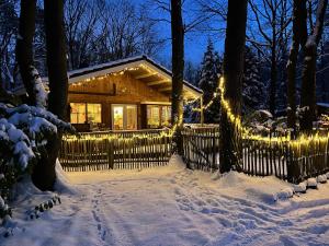 une maison recouverte de lumières de Noël dans la neige dans l'établissement Vakantiechalet voor 4 plus 2 met sauna, à Lanaken