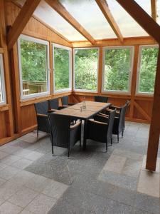 ein Esszimmer mit einem Tisch, Stühlen und Fenstern in der Unterkunft Ferienhaus Star Villa-Pälitzsee in Großzerlang