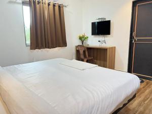 1 dormitorio con 1 cama blanca y TV en Hotel Karna Residency , Ranjangaon, en Ranjangaon