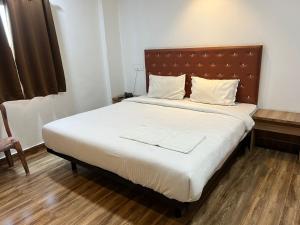 1 dormitorio con 1 cama grande y cabecero de madera en Hotel Karna Residency , Ranjangaon, en Ranjangaon