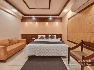 a bedroom with a bed and a chair and a couch at Hotel Royal Wings in Elūr