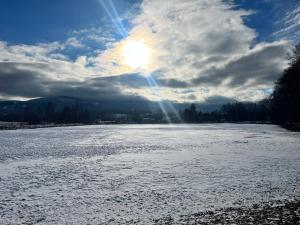 a snow covered river with the sun in the sky at Sarnia Polana in Kostrzyca