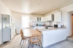 eine Küche mit weißen Schränken sowie einem Tisch und Stühlen in der Unterkunft Douce parenthese en Vendee in Saint-Michel-en-lʼHerm