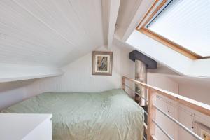 ein kleines Schlafzimmer im Dachgeschoss mit einem Bett und einem Fenster in der Unterkunft Douce parenthese en Vendee in Saint-Michel-en-lʼHerm