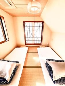 2 camas en una habitación pequeña con ventana en 吉吉の家, en Tokio