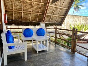 Surya Beach Resort Palawan في Aborlan: شرفة مع كراسي بيضاء ووسائد زرقاء