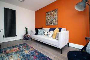 a living room with a white couch and an orange wall at Cohost Partners Spacious Free Parking in Cardiff