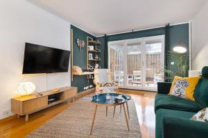 a living room with a green couch and a tv at T3 - PARIS 10' Confort & Modern - Terrasse - Parking - WIFI in Gentilly