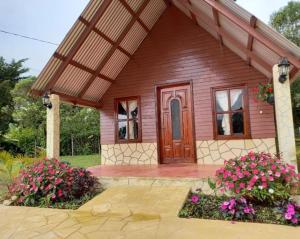 uma pequena casa de madeira com flores em frente em Cabañas camino real em Santiago