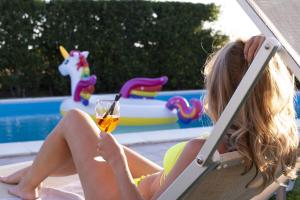 Eine Frau auf einem Stuhl mit einem Glas Wein am Pool in der Unterkunft La Casa del Fico villa con piscina in Pescia Romana