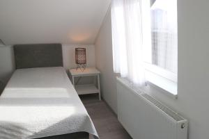 a small bedroom with a bed and a window at Laganini, apartman 6 Tri Sky in Nova Gradiška