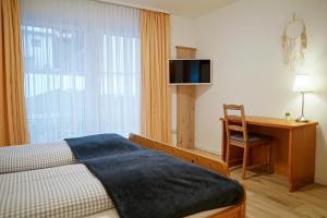 um quarto com uma cama, uma secretária e uma janela em HoFer am Zeitberg Ferienwohnung Wildeck em Bad Kohlgrub