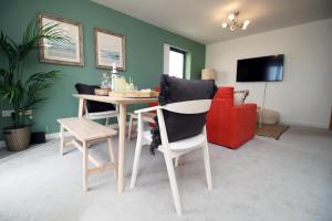 a living room with a table and a red couch at Observatory 2 bedroom apartment overlooking Beach in Swansea