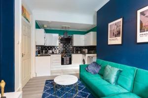 a living room with a green couch and a kitchen at Boutique and Beautiful Edinburgh Abode in Edinburgh