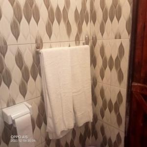 La salle de bains est pourvue de serviettes blanches accrochées au mur. dans l'établissement Gever’s paradise, à Watamu