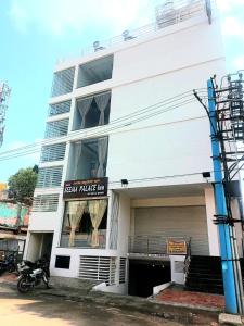 - un bâtiment blanc avec un panneau indiquant l'auberge du palais social dans l'établissement Seema Palace Inn, à Mysore