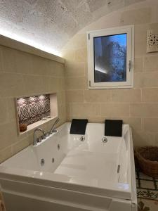 La salle de bains est pourvue d'une baignoire blanche et d'une télévision. dans l'établissement B&B Lo Scrigno del Salento, à Sava