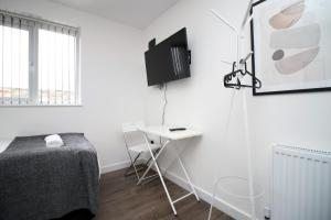 Habitación con cama, escritorio y TV. en Cohost Partners | Smart TV | 5 Min City | Parking, en Cardiff
