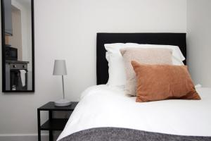 a white bed with a brown pillow on it at Smart TV | WiFi | Attractions in Cardiff