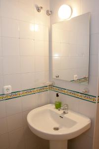 bagno bianco con lavandino e specchio di Apartamento Torre de la Plata a Siviglia