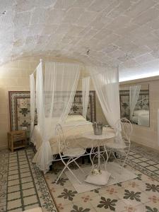 a bedroom with a canopy bed with a table and chairs at B&B Lo Scrigno del Salento in Sava