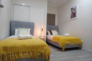 a bedroom with two beds and a yellow blanket at Entire house in Pimpama in Gold Coast