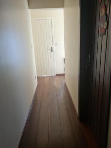 an empty hallway with a wooden floor and a door at Aluguel de quarto in Torres