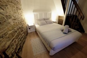 a bed in a room with a stone wall at la Ferme de Vazerat in Massiac