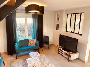 een woonkamer met een blauwe bank en een televisie bij LA MARIEFACTURE - Comme un Tour du Monde 