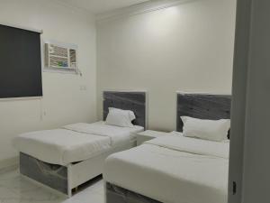 2 Betten in einem Zimmer mit weißen Wänden in der Unterkunft دلتا2للوحدات المخدومة بالدوادمي in Ad-Dawādimi