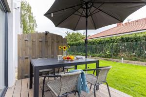 einen schwarzen Tisch und Stühle mit Sonnenschirm auf einer Terrasse in der Unterkunft Solo na wyspie, blisko morza Sobieszewo in Danzig