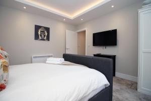 um quarto com uma cama branca e uma televisão de ecrã plano em Newport Road (FREE Parking) em Cardiff