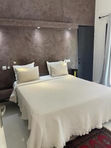 duże białe łóżko z białą pościelą i poduszkami w obiekcie Villa Le Petit Paradis Saly Boutique Hotel w mieście Ngaparou