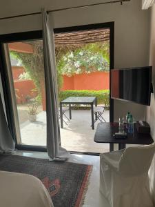 a living room with a sliding glass door with a table and a television at Villa Le Petit Paradis Saly Boutique Hotel in Ngaparou