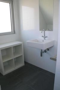 baño blanco con lavabo y ventana en Lamsoor 14*, en Nieuwvliet