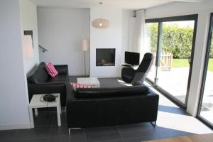 sala de estar con sofá negro y mesa en Lamsoor 14*, en Nieuwvliet