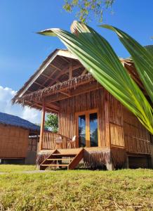 une maison en bambou avec un palmier en face de celle-ci dans l'établissement Kahoy Cottages, à Siquijor