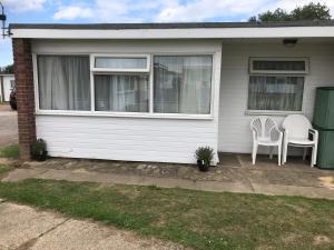 a house with two white chairs on the porch at Captivating 2-Bed Chalet in Great Yarmouth in Great Yarmouth