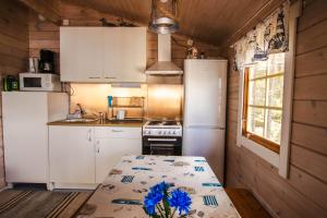 a kitchen with white appliances and a table with blue flowers on it at Västeräng Glamping in Lillandet