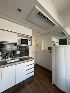 an empty kitchen with white cabinets and a refrigerator at Studio Living Slavieiro Moema in Sao Paulo