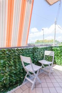 2 chaises assises sur une terrasse à côté d'une haie dans l'établissement SuiteHouse - Jacuzzi & Comfort, à San Giorgio a Cremano