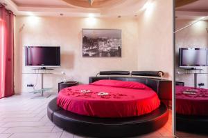 Cette chambre comprend un grand lit rouge et une télévision. dans l'établissement SuiteHouse - Jacuzzi & Comfort, à San Giorgio a Cremano
