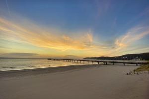 a pier stretches out over the beach at sunset at Haus Godewind Ferienwohnung 10 mit Balkon und Strandkorb in Binz