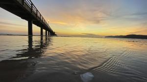 a pier on the water with the sunset in the background at Haus Godewind Ferienwohnung 5 mit Balkon und Strandkorb in Binz