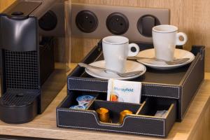 a tray with two cups and plates in a microwave at Hotel Charlemagne in Neuilly-sur-Seine