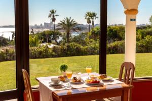 a table with food and drinks and a view of the ocean at Hotel Casabela in Ferragudo