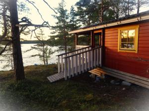 Cabaña roja pequeña con porche y ventana en Västeräng Glamping en Lillandet