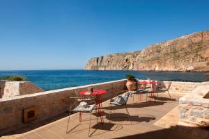 a patio with tables and chairs and the ocean at Kyrimai Hotel in Yerolimin